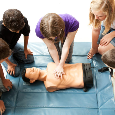 Teenage students use a mannequin to practice life saving techniques.