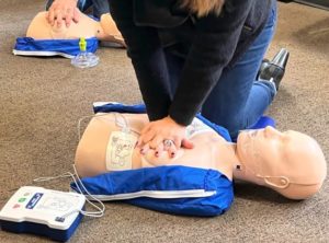 A person practices CPR on a PRESTAN Products training manikin that includes the new PRESTAN Female Accessory