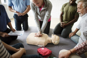 A group of people practices CPR skills on a training manikin.