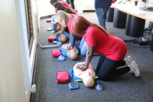 A group of WorldPoint employees practice their hands-only resuscitation skills during a training exercise featuring WorldPoint training manikins.