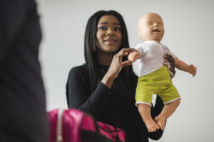 A CPR training instructor holds up Baby Taylor, an infant-sized training manikin developed by WorldPoint.